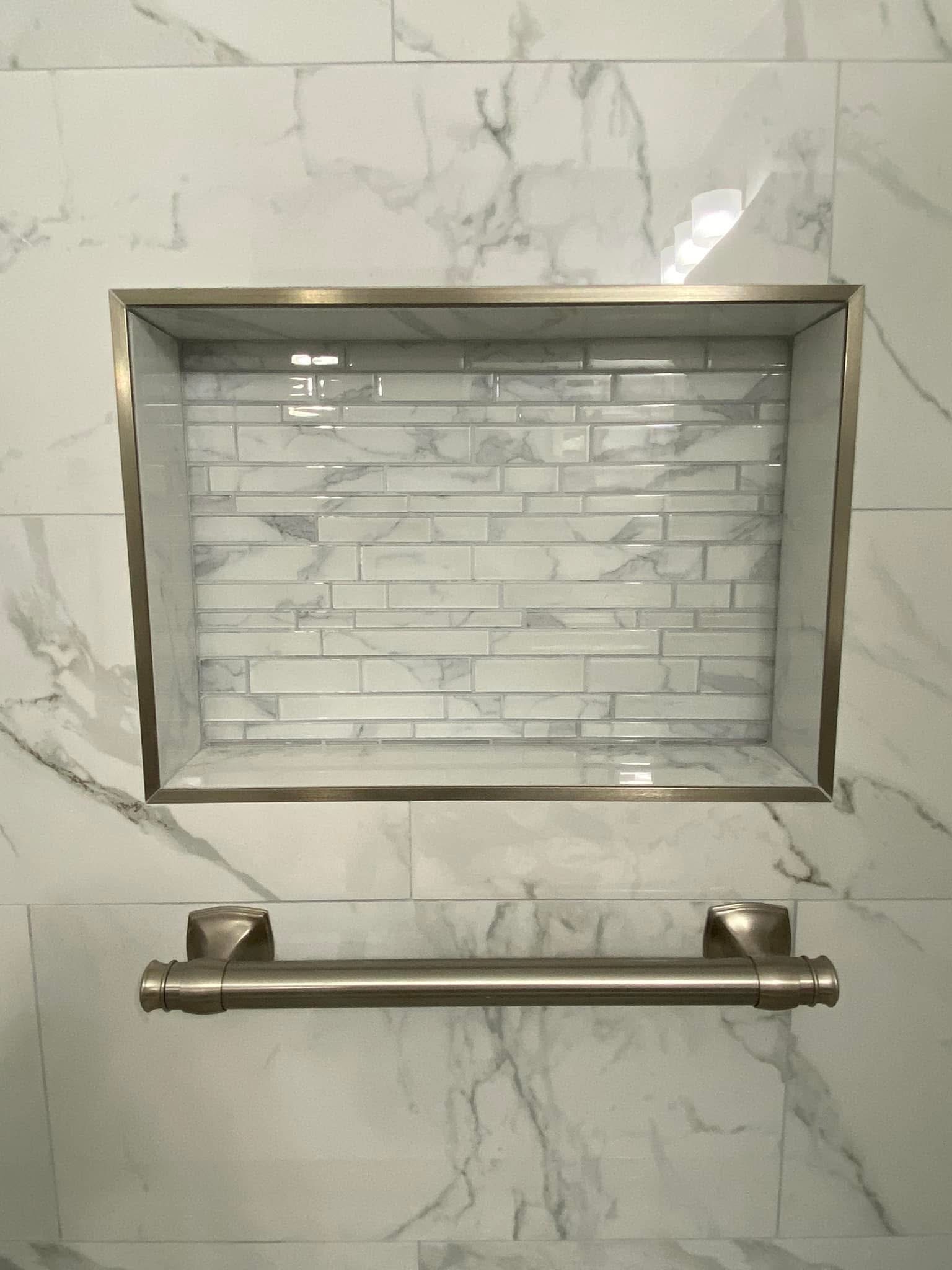 Shower niche with marble-look mosaic tile and brushed metal trim