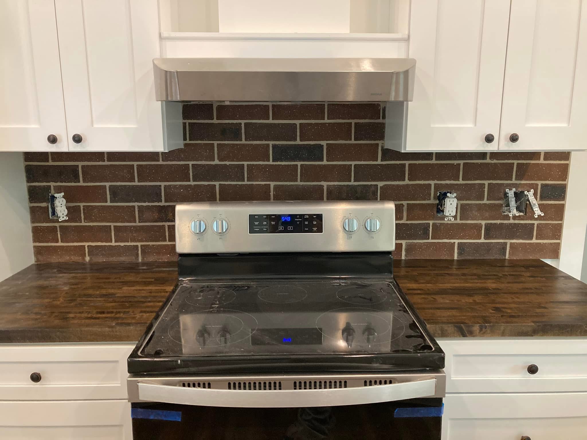 Dark subway tile backsplash behind a kitchen range