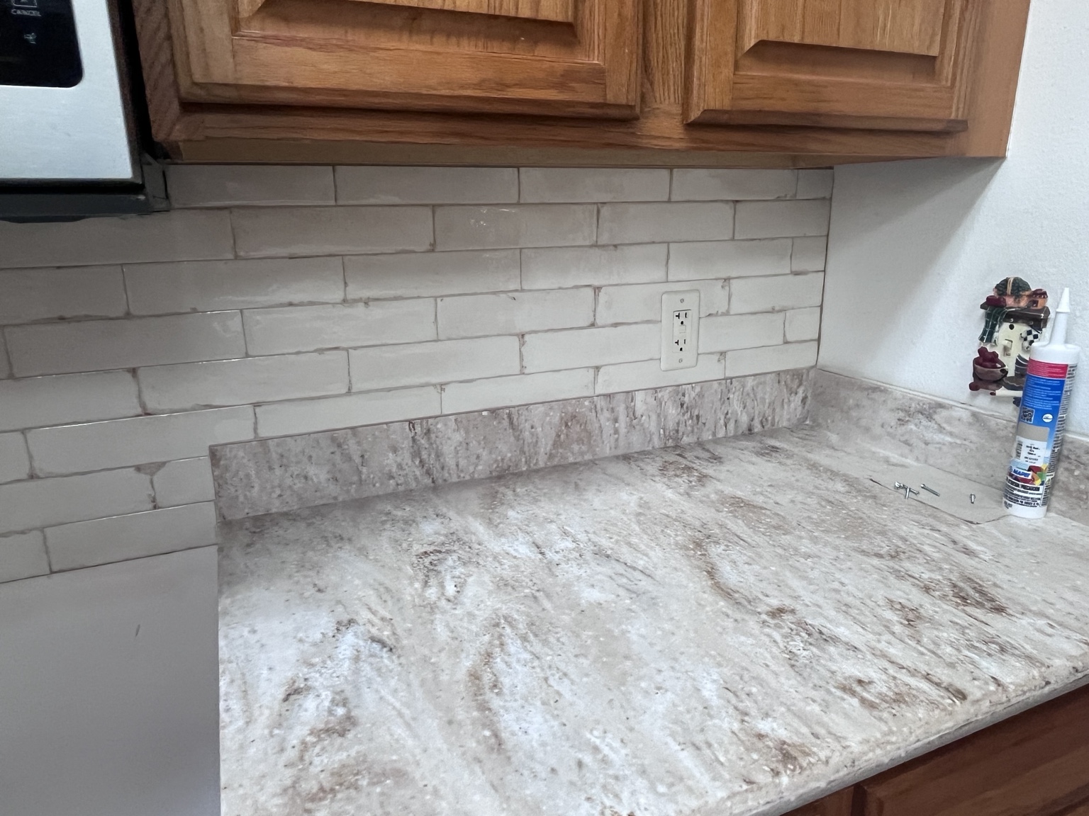 White subway tile backsplash over stone-look countertop