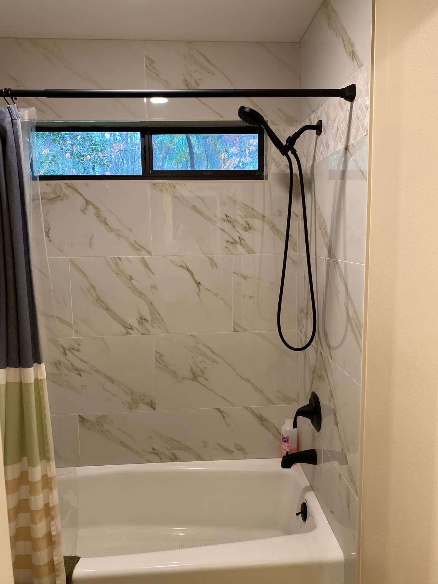 Bathtub with stone-look tile and black shower fixtures