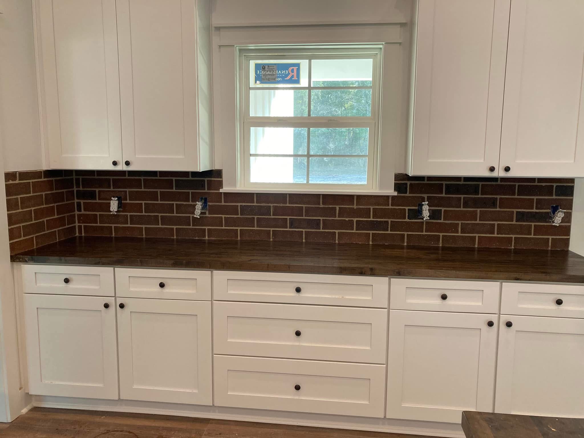 Brown tile backsplash in a white cabinet kitchen
