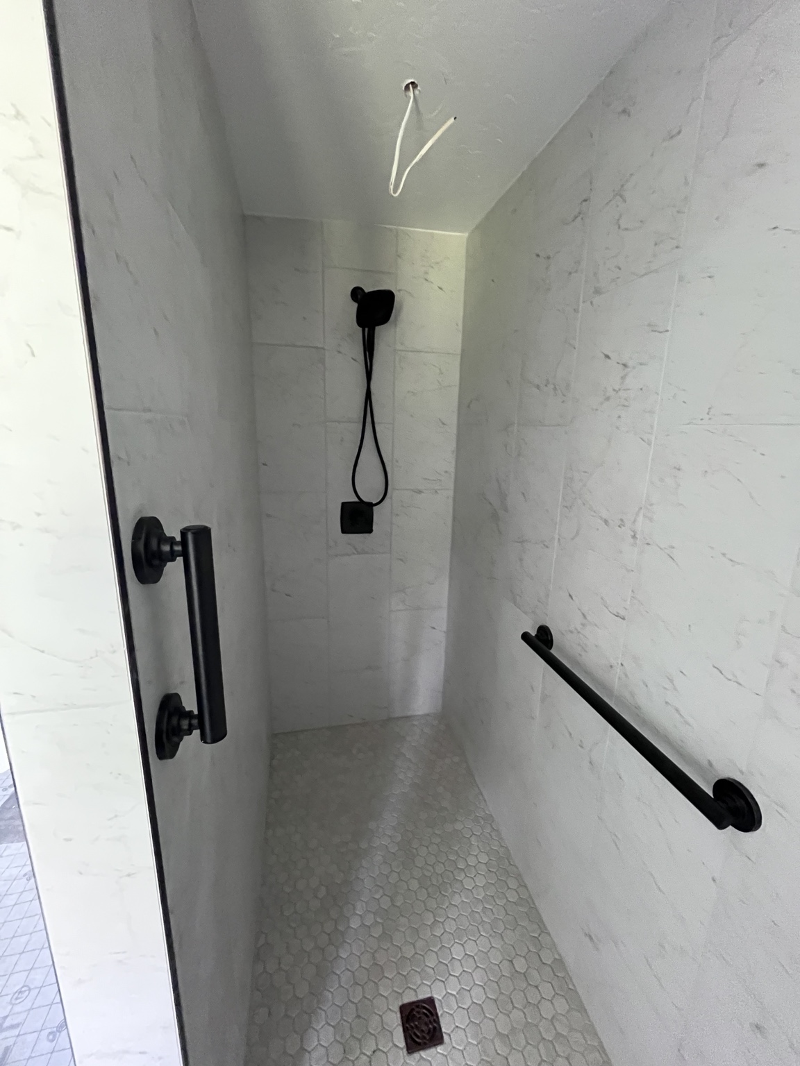 Walk-in shower with grab bar and white tile