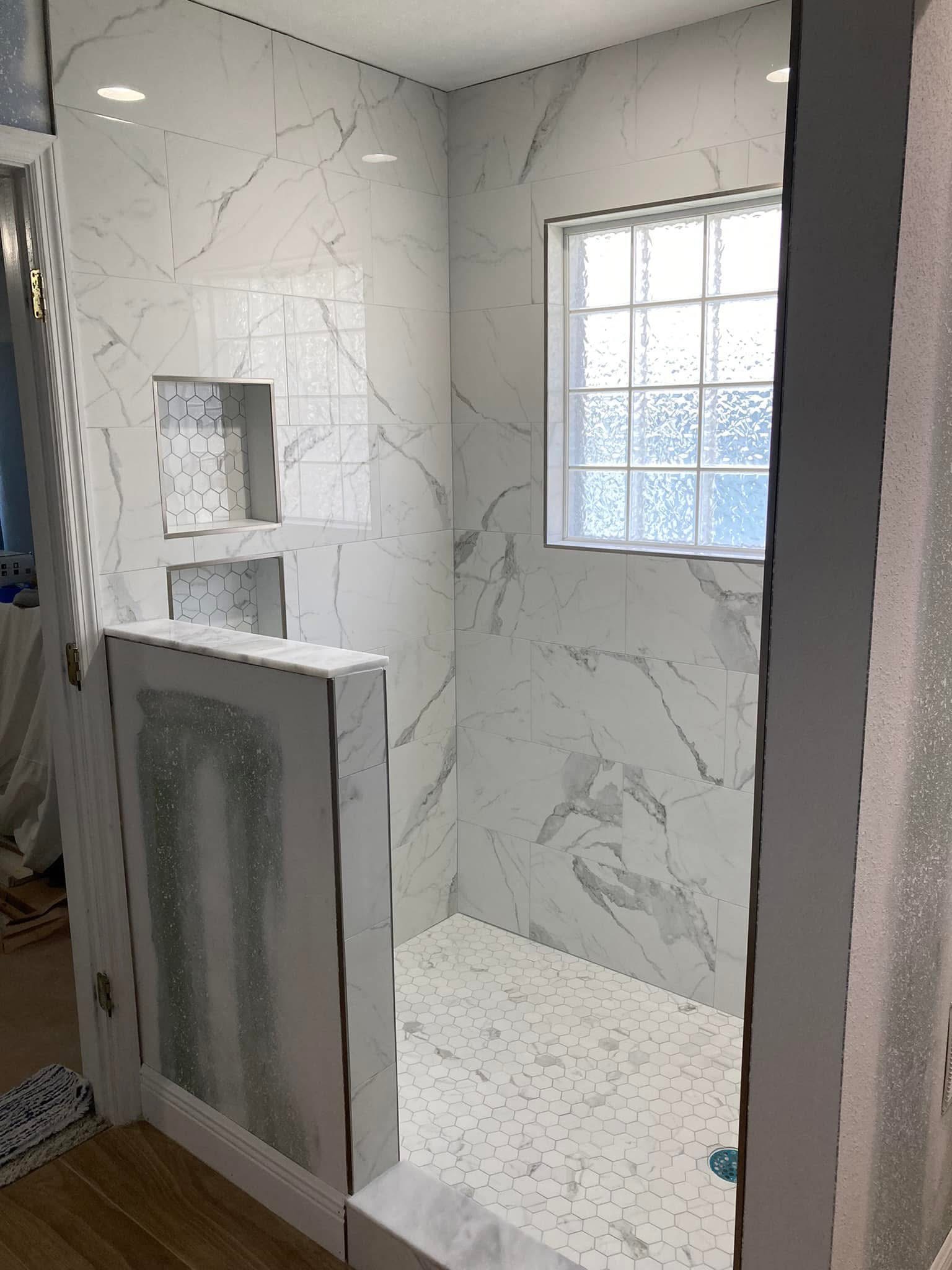 Marble-look shower with two niches and a window