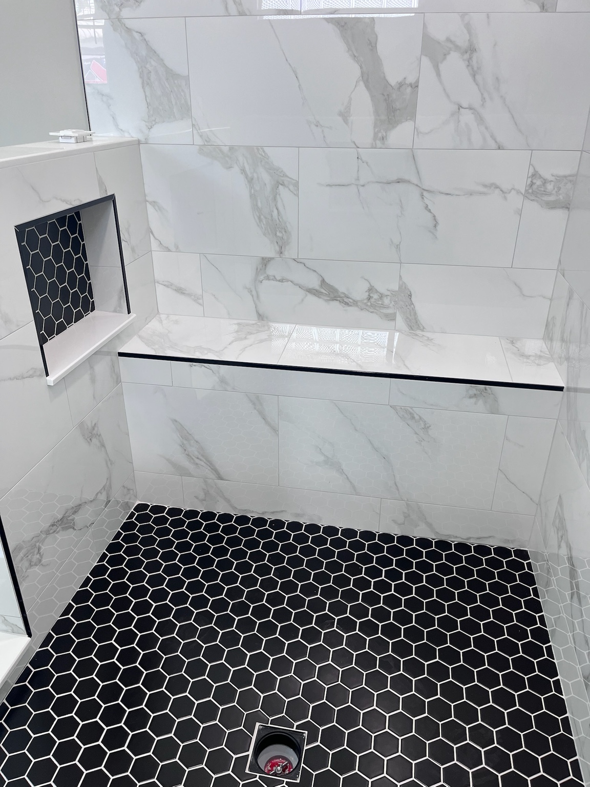 Shower niche and dark hexagon floor tile