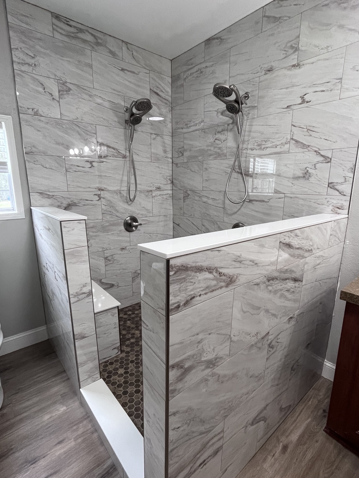 Two-head tiled shower with half walls and stone mosaic floor