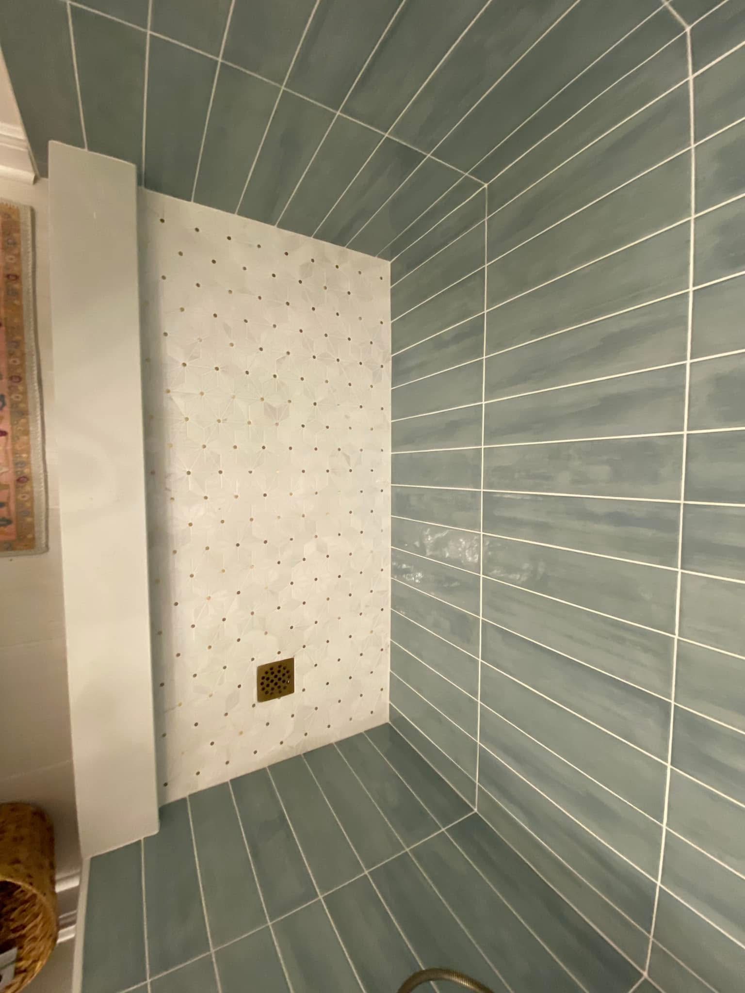 Green tiled shower wall with stone-look shower floor