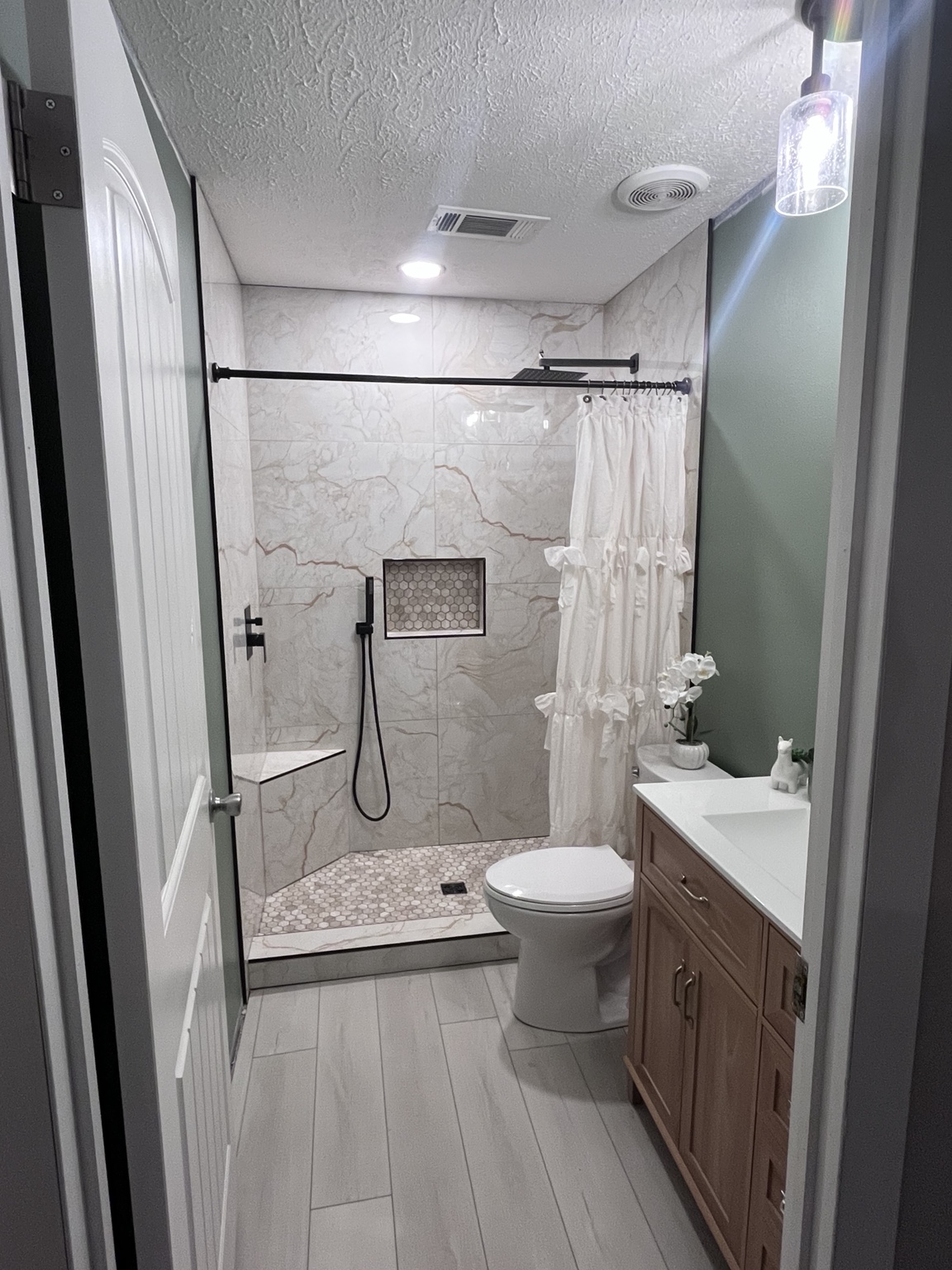 Bathroom with walk-in shower, wood vanity, and tile floor