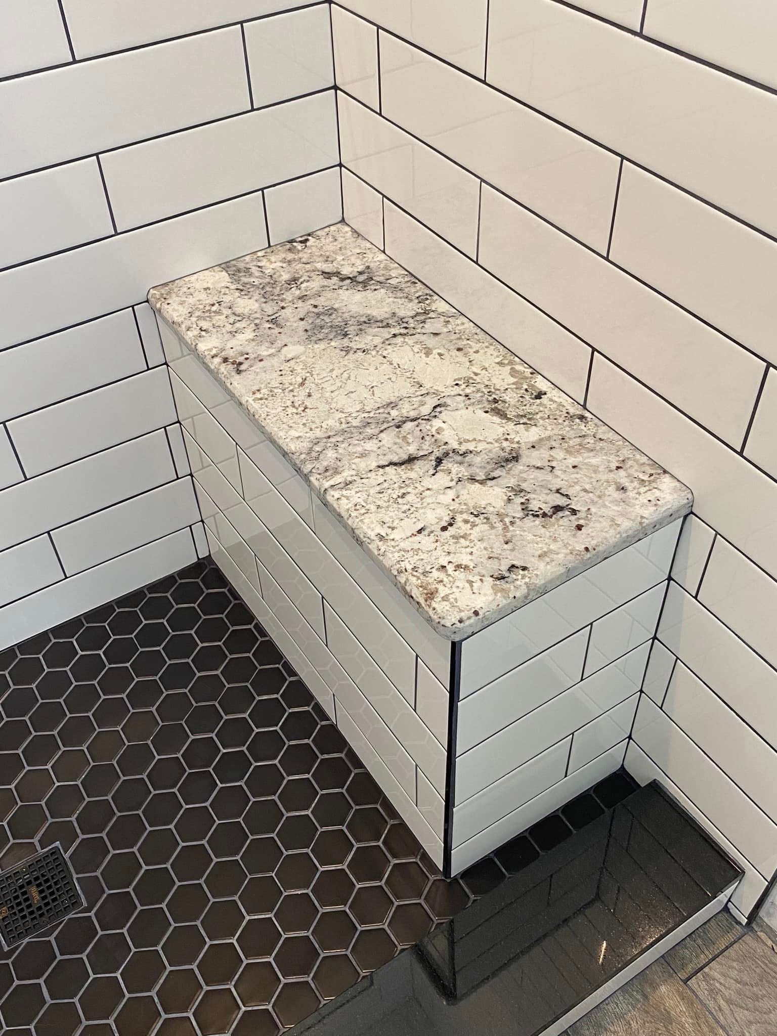 Stone-topped shower bench against white subway tile