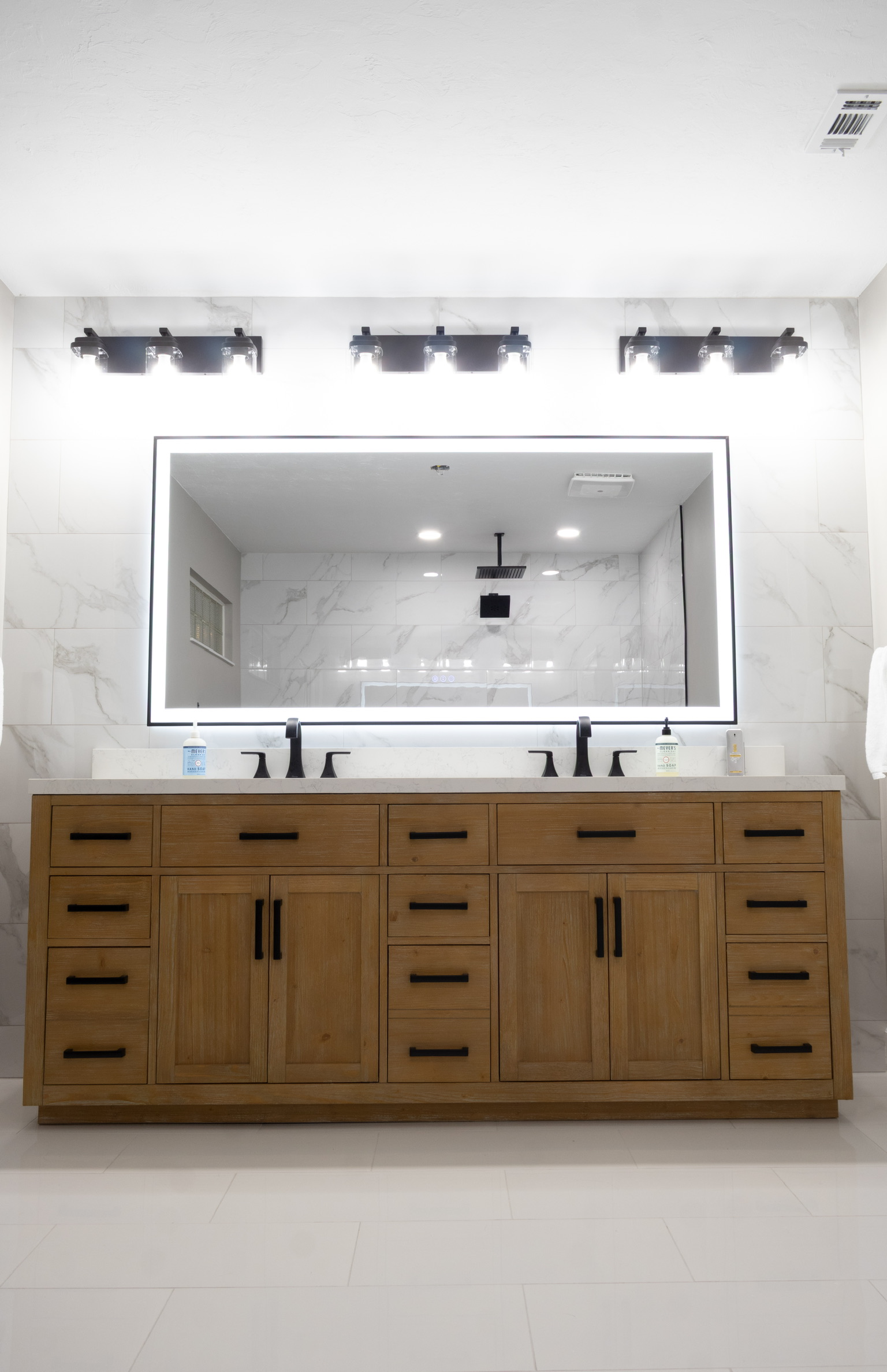 Double vanity with lighted mirror and wood cabinetry