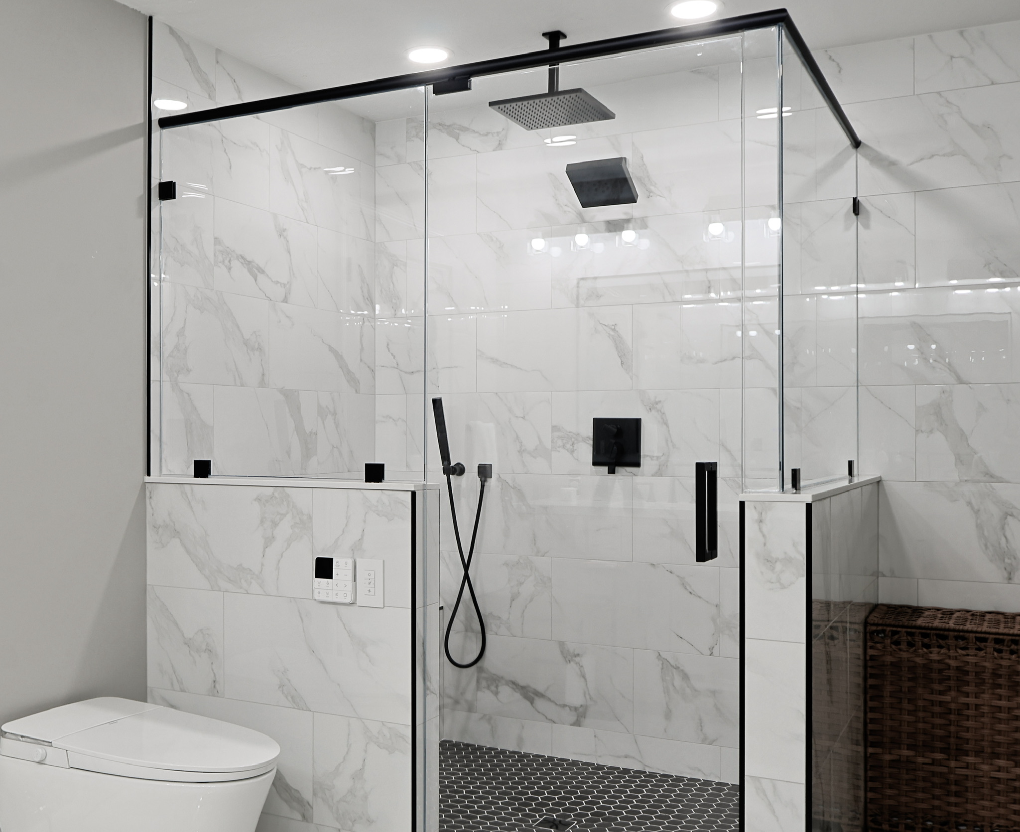 Glass shower enclosure with black fixtures and marble-look tile